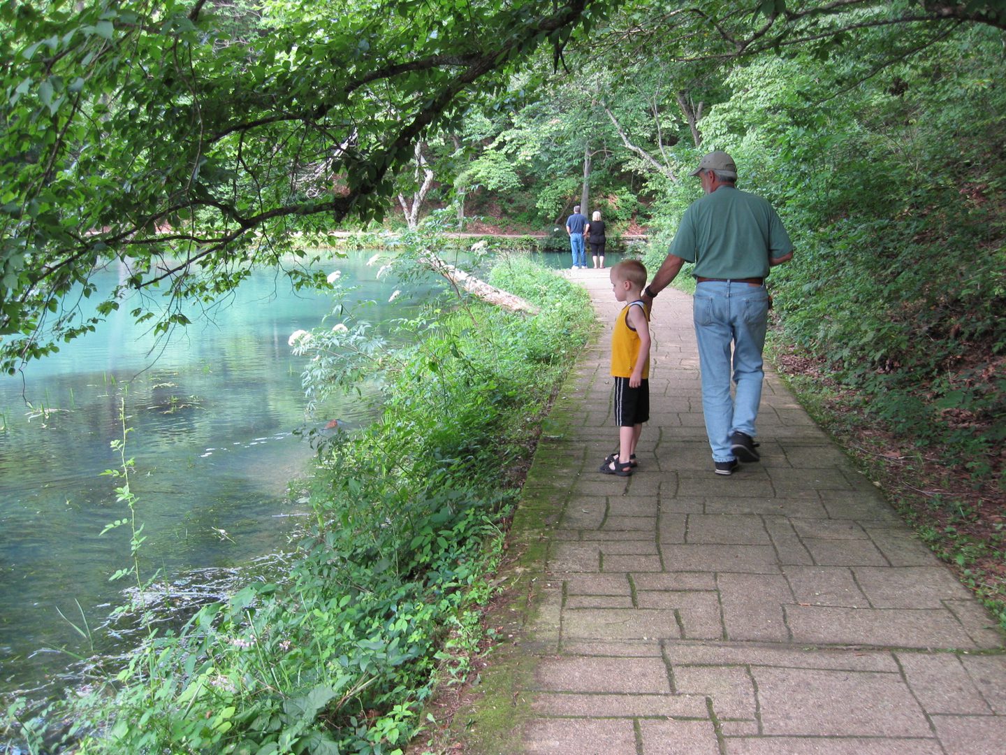 Grandfather and grandson walking by the lake.