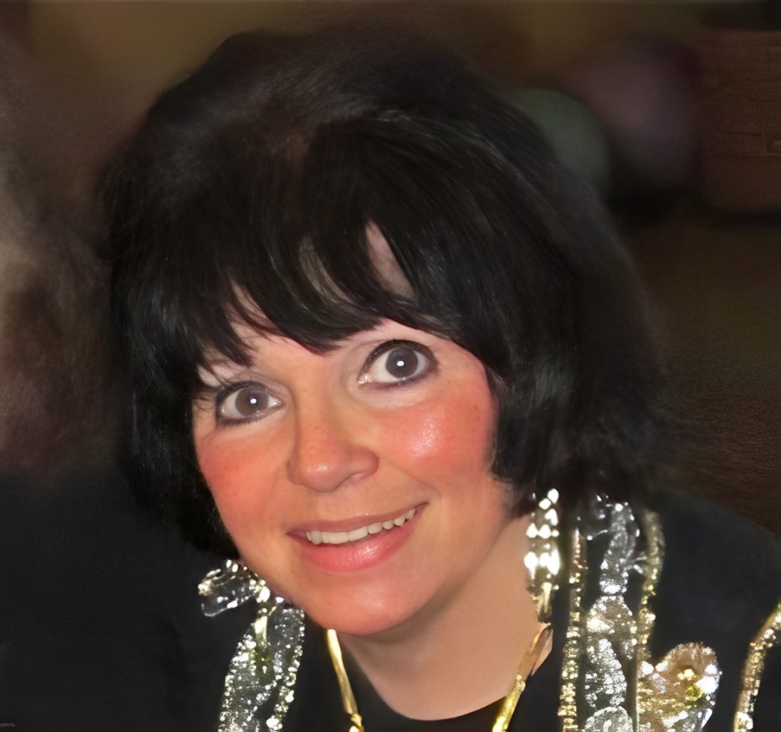 Smiling woman with dark hair and jewelry.