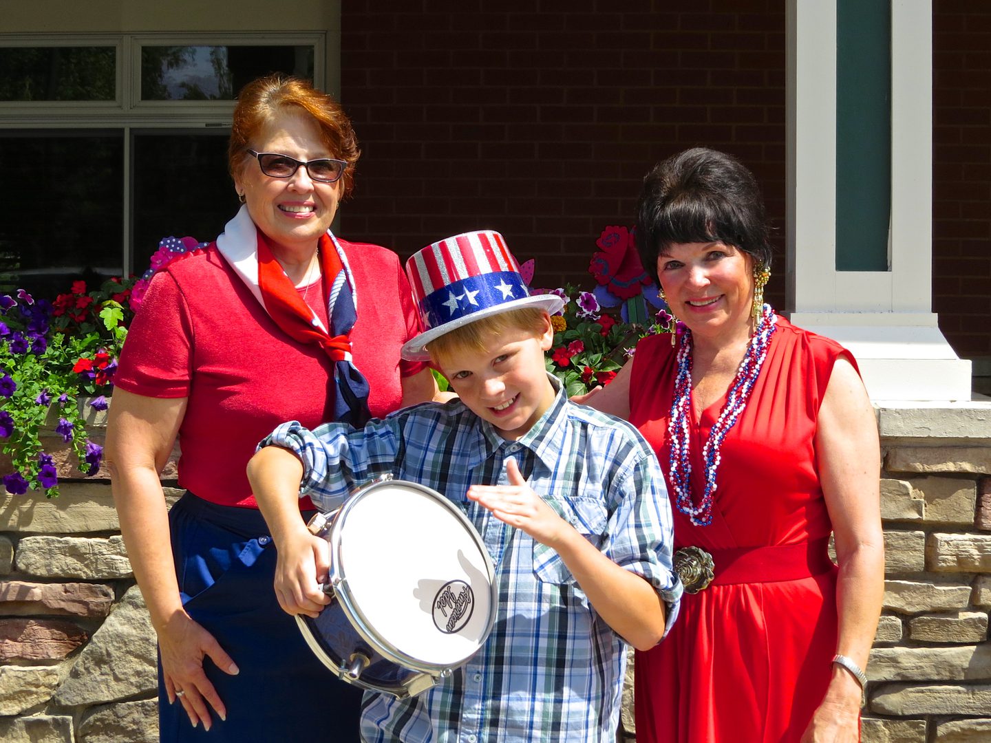 Boy with drum and two women smiling.