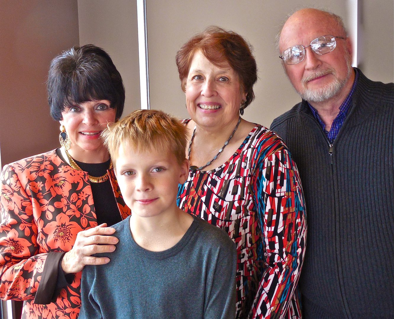 Four people smiling, including a child.