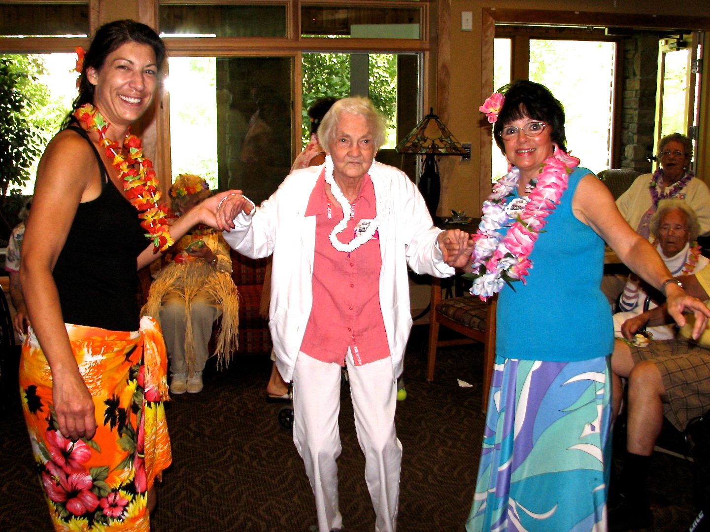 Three women dancing in colorful Hawaiian attire.