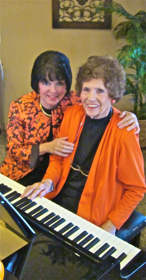 Two women smiling beside a keyboard.