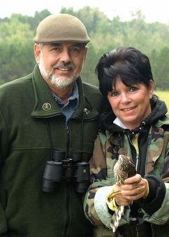 Couple outdoors holding a small bird.