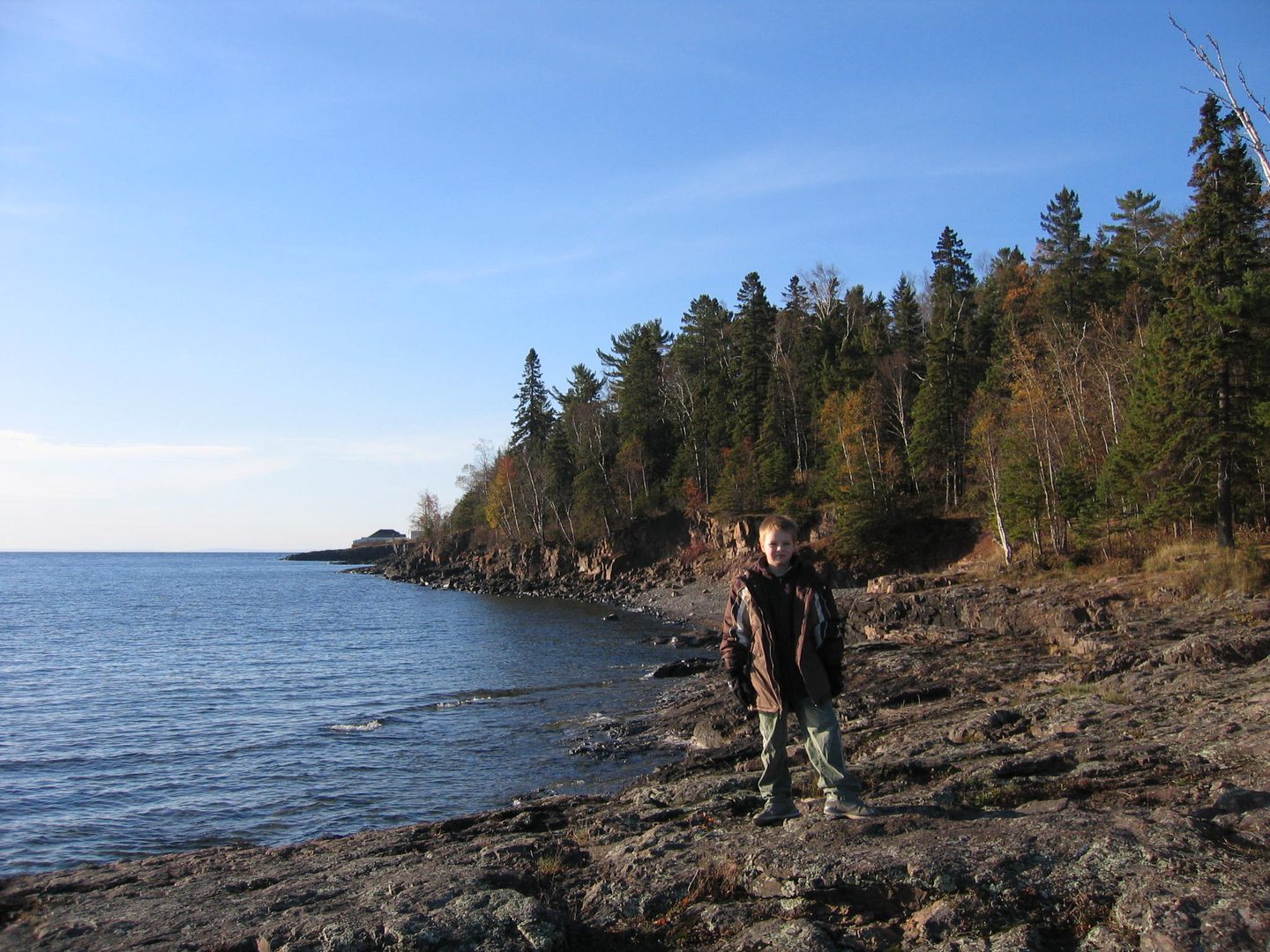 Person standing on rocky lakeside shore.