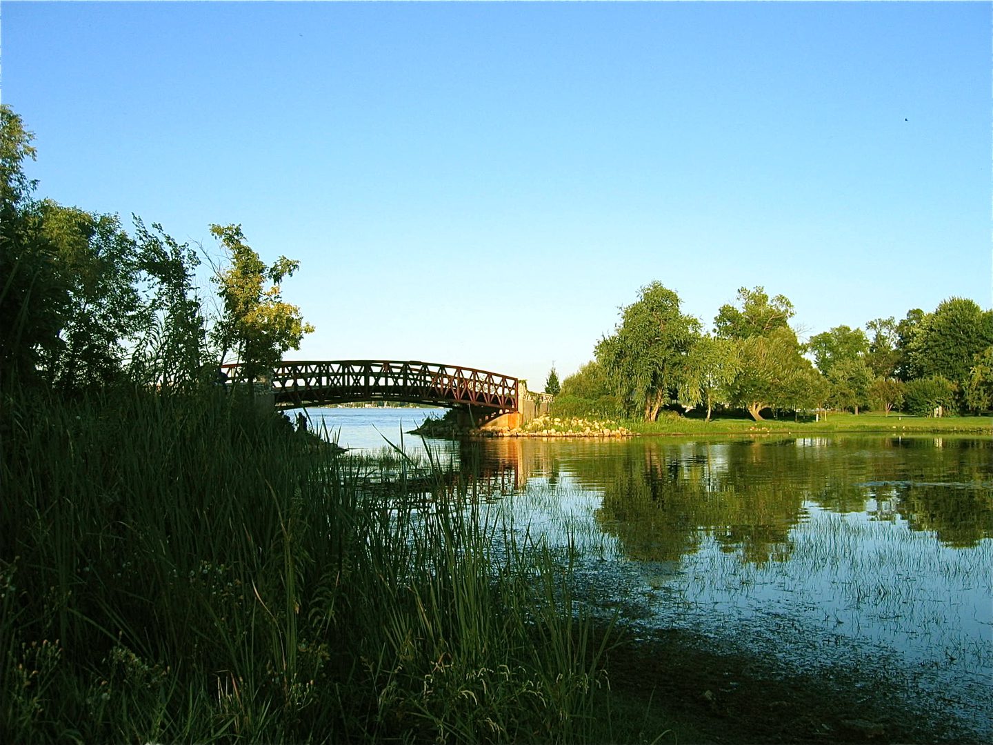 Bridge over calm river with trees.