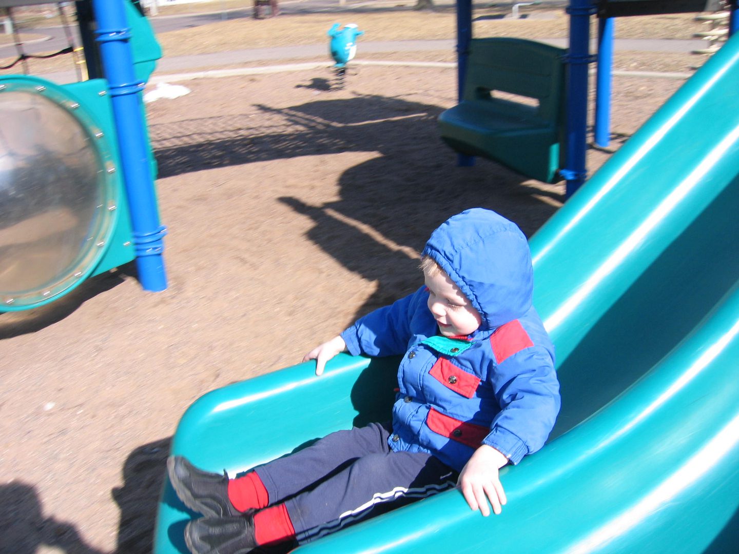 Child sliding down blue playground slide.