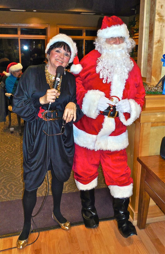 Woman singing with Santa at event.
