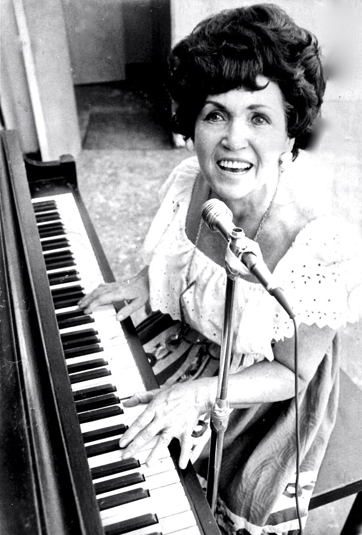 Woman playing piano and singing passionately.