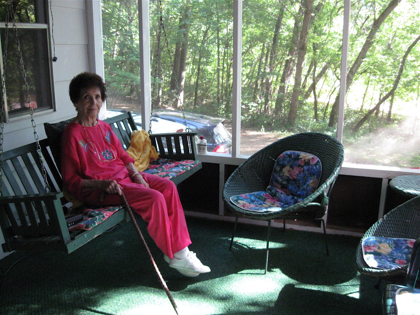 Woman sitting on porch with walking cane.