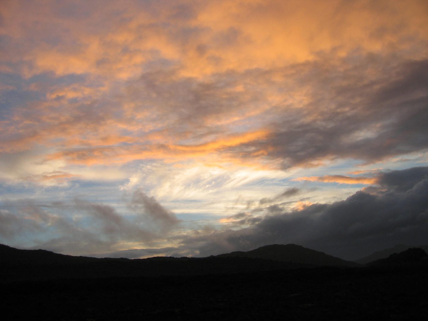 Orange and gray clouds over distant hills.