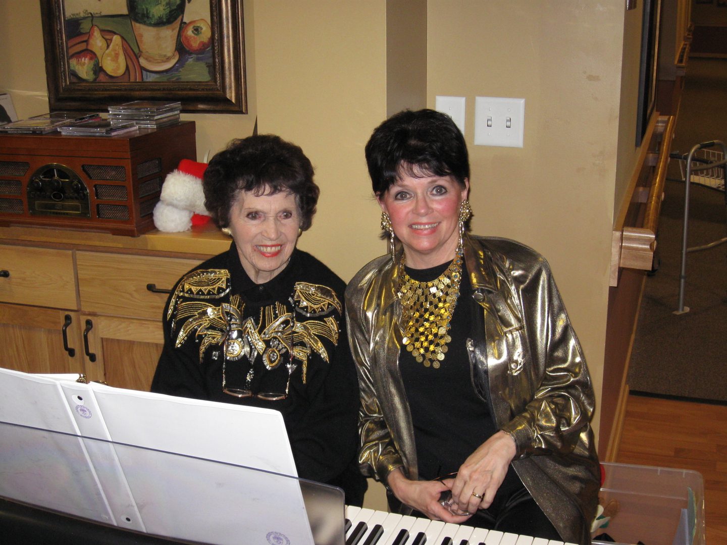 Two women sitting at a keyboard.