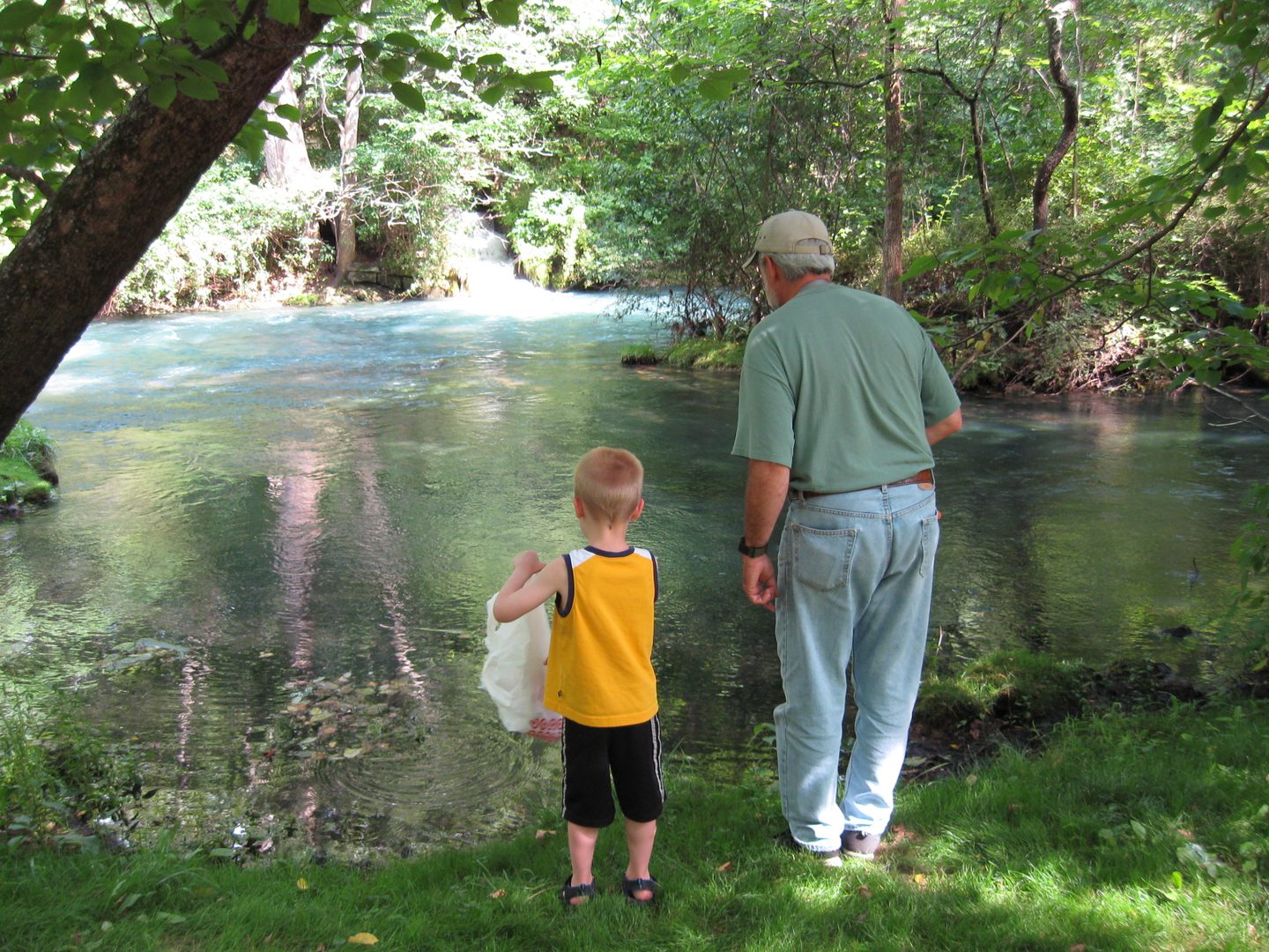 Man and child standing by a river.