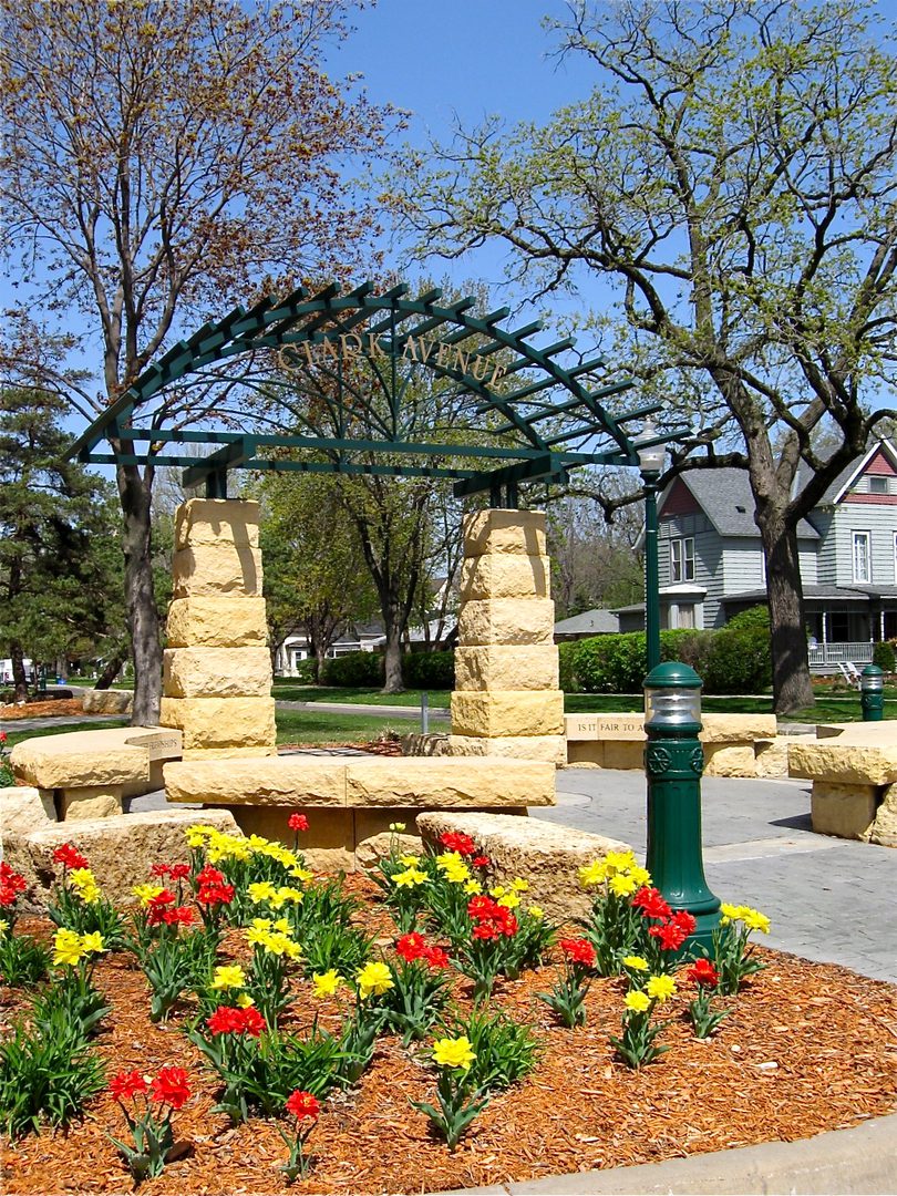 Park entrance with colorful flowers and trees.