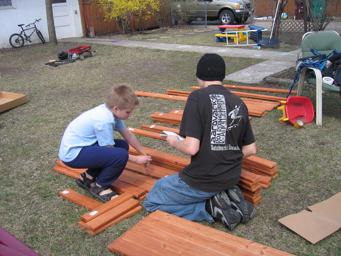 Two people assembling wooden planks outdoors.