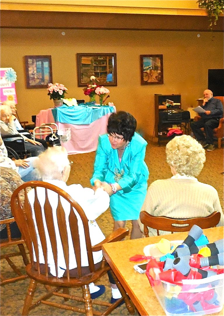 Woman interacting with seated elderly people.
